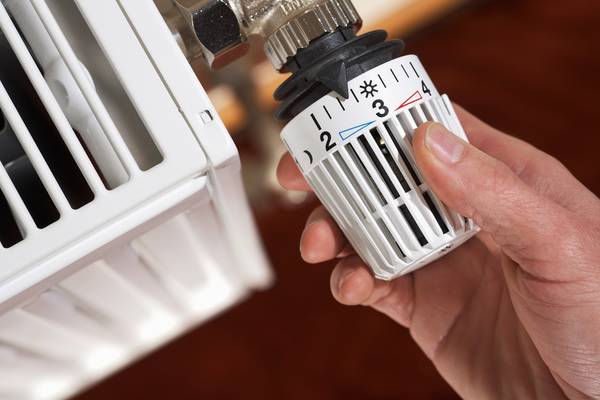 Foto einer Hand, die ein Thermostat unterregelt