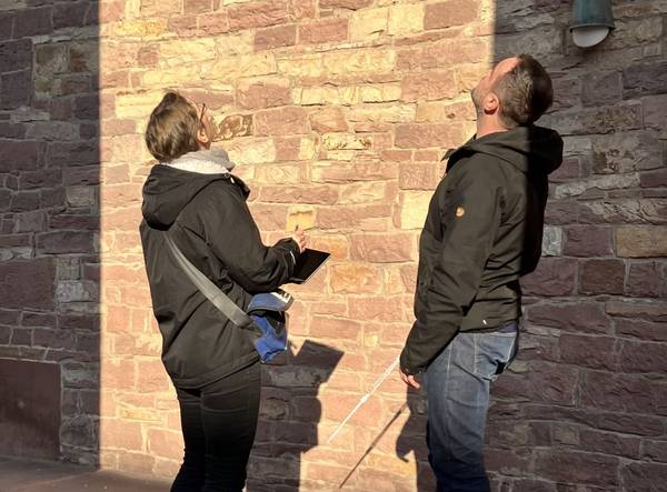 Foto einer Gebäudeanalyse zwei Menschen betrachten eine Kirchenmauer