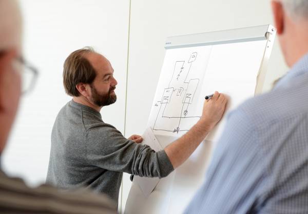 Person zeichnet Bauplan auf eine Leinwand