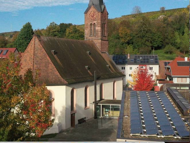 Foto der Solarmodule auf dem Dach des Gemeindehauses mit der Kirche im Hintergrund