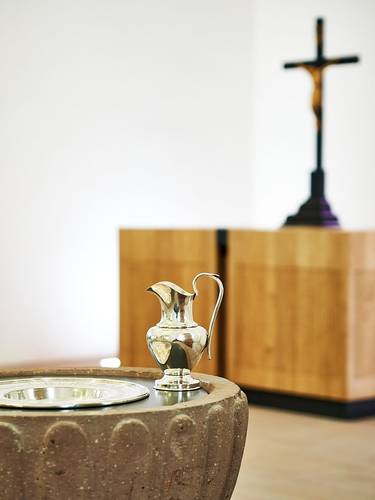 Foto des Altars in Holzoptik und des steinernen Taufbeckens der Kirche