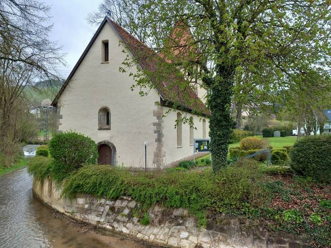 Foto der Kirche in Oberschüpf von der Straße aus mit großem Baum vor dem Kirchenschiff