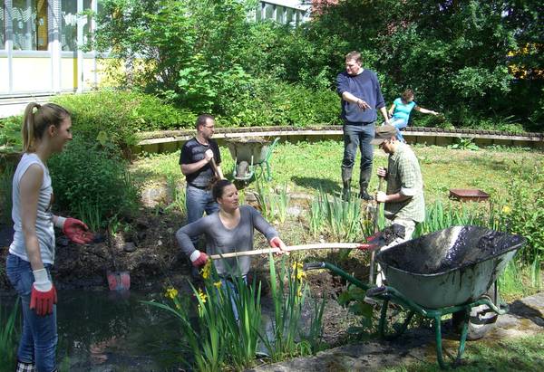 Teich in einem Garten, in dem Menschen arbeiten